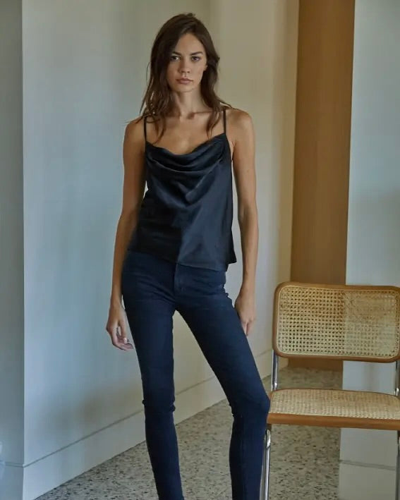 Model wearing By Together Satin Camisole in black wearing jeans standing next to a chair