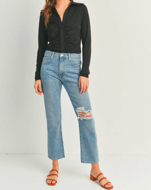 Model wearing Just Black Denim High Rise 90's Jean Light Wash wearing a black blouse and brown shoes on a white background