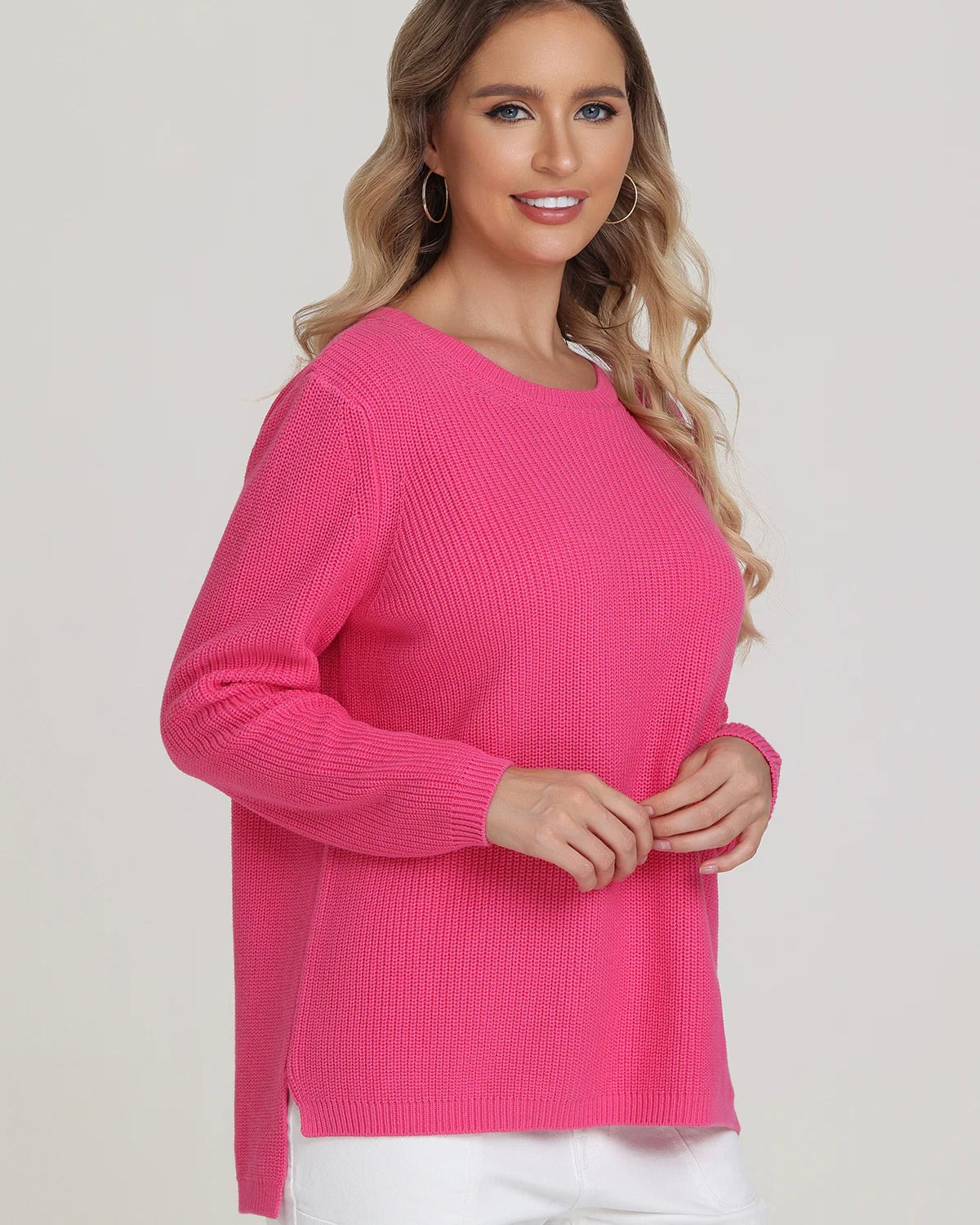 Model wearing 525 America Emma Crewneck Shaker Stitch Sweater in shocking pink color wearing white pants on a white background