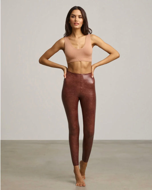 Model wearing Commando faux brown leather animal leggings wearing nude bra on a white background