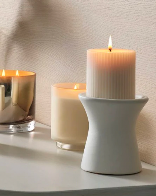 image of ILLUME winter white small fragranced pillar candle on a white candle holder 