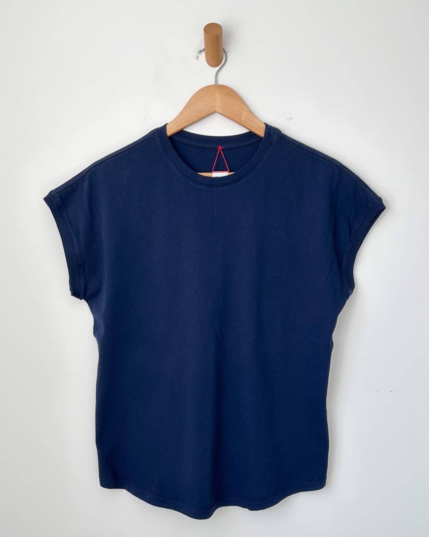 Navy blue sleeveless top on a wooden hanger against a white background