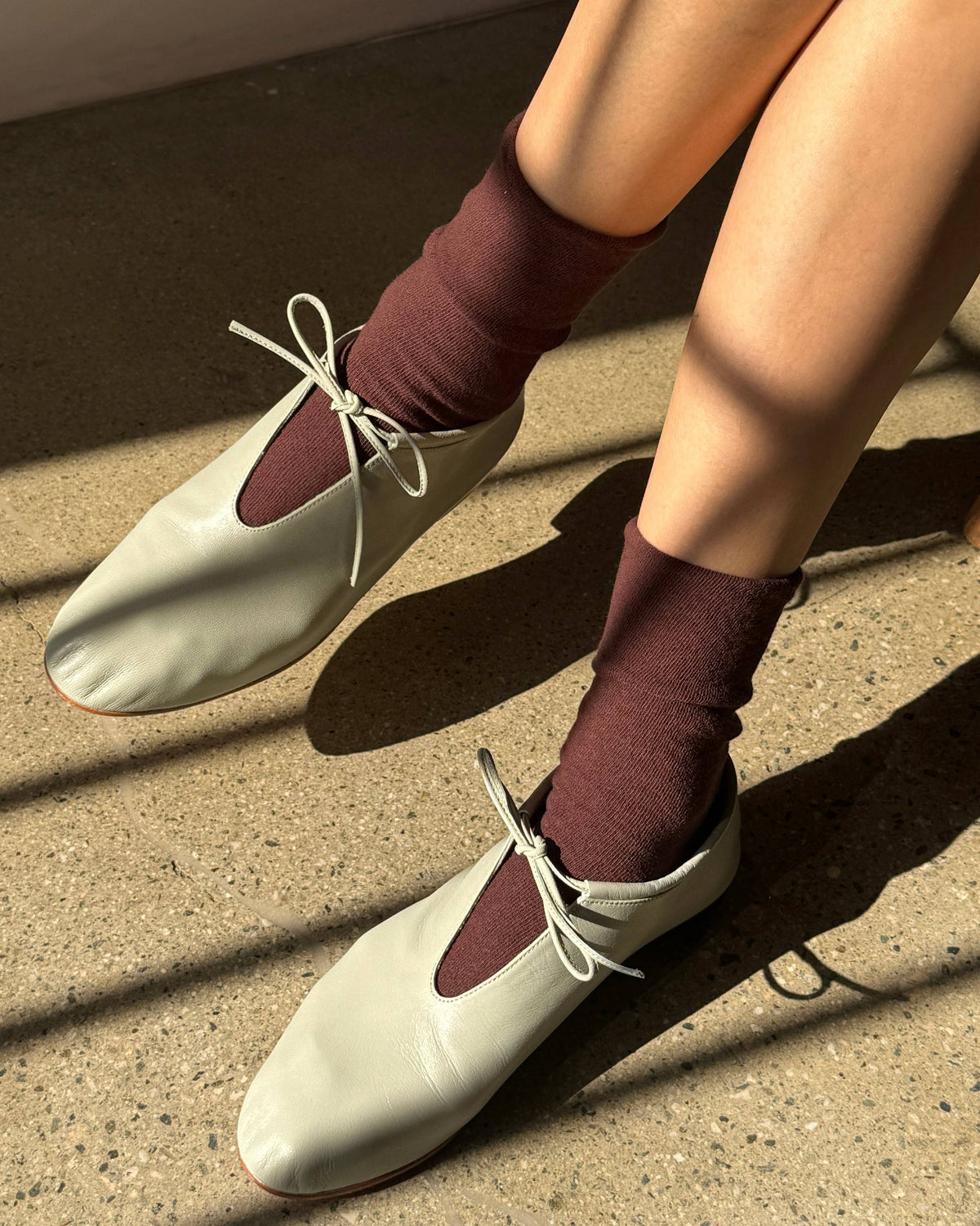 White shoes and maroon socks on a concrete surface