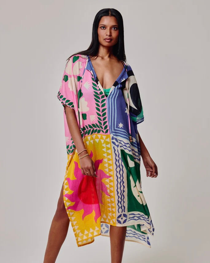 Woman wearing a colorful patterned dress on a plain background