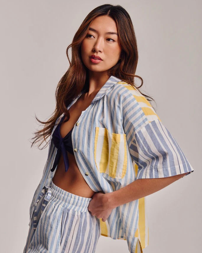 Woman wearing a striped shirt and shorts with a neutral background