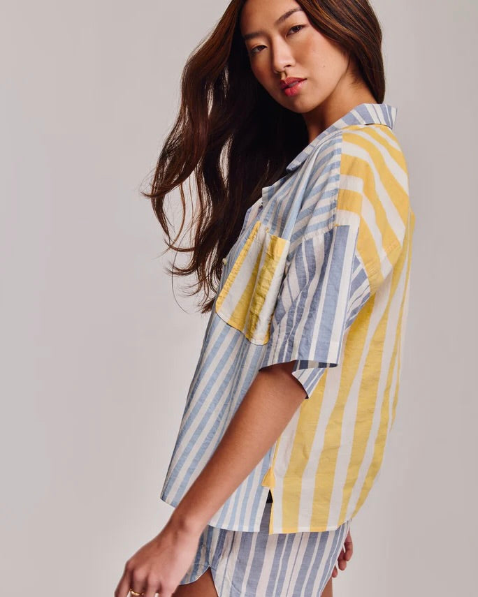 Woman wearing a yellow and blue striped shirt against a plain background
