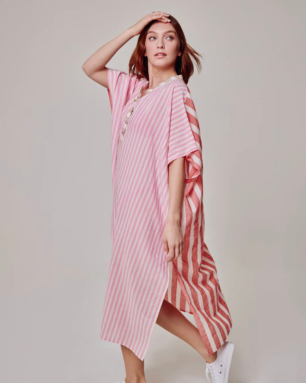 Woman wearing a pink and white striped dress on a plain background