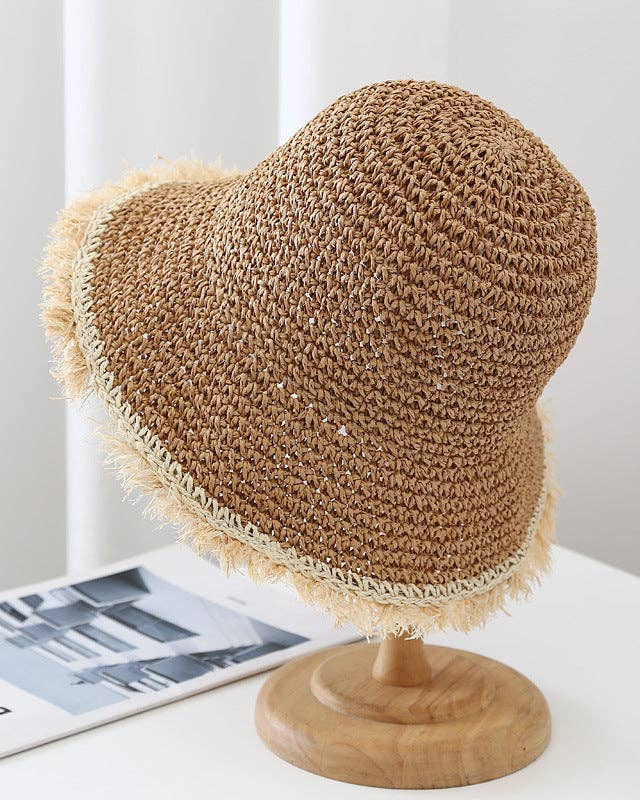 Brown crochet hat on a wooden stand with a white background