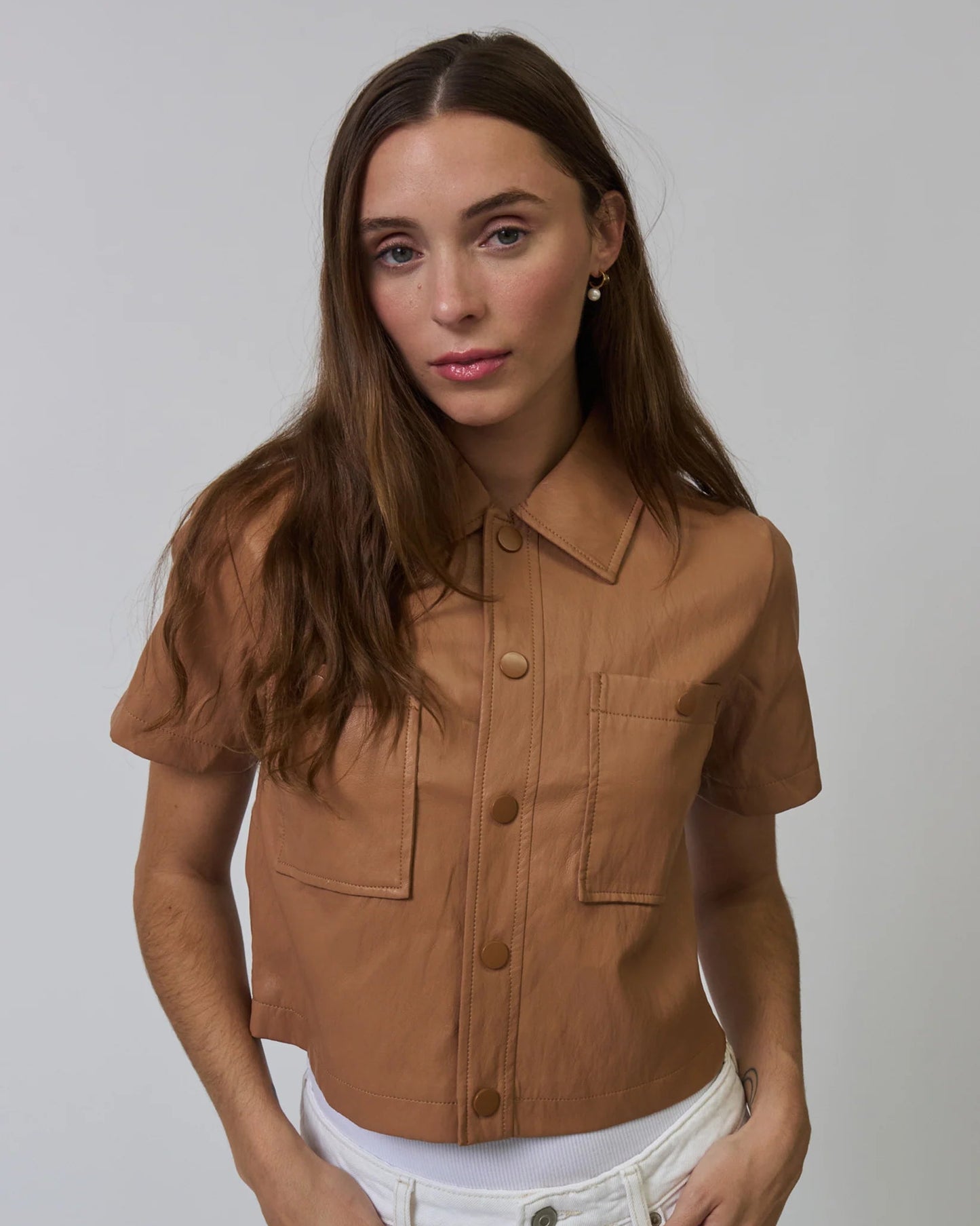 Woman wearing a brown short-sleeve shirt against a plain background