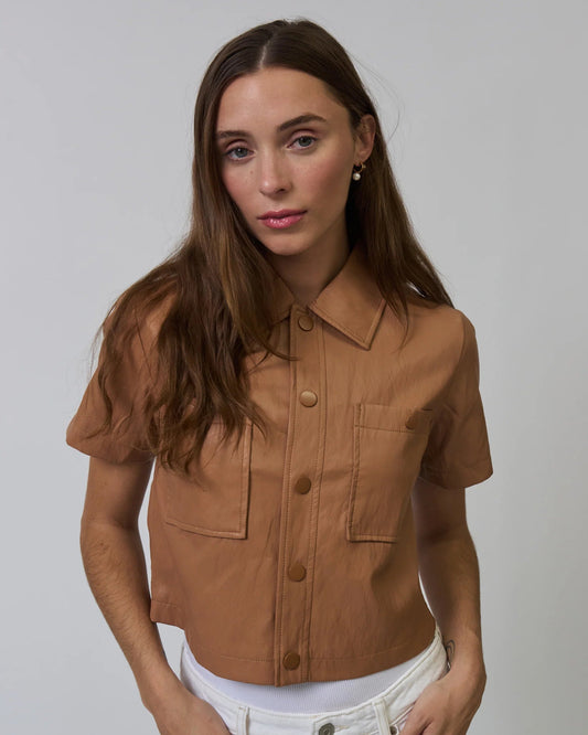 Woman wearing a brown short-sleeve shirt against a plain background