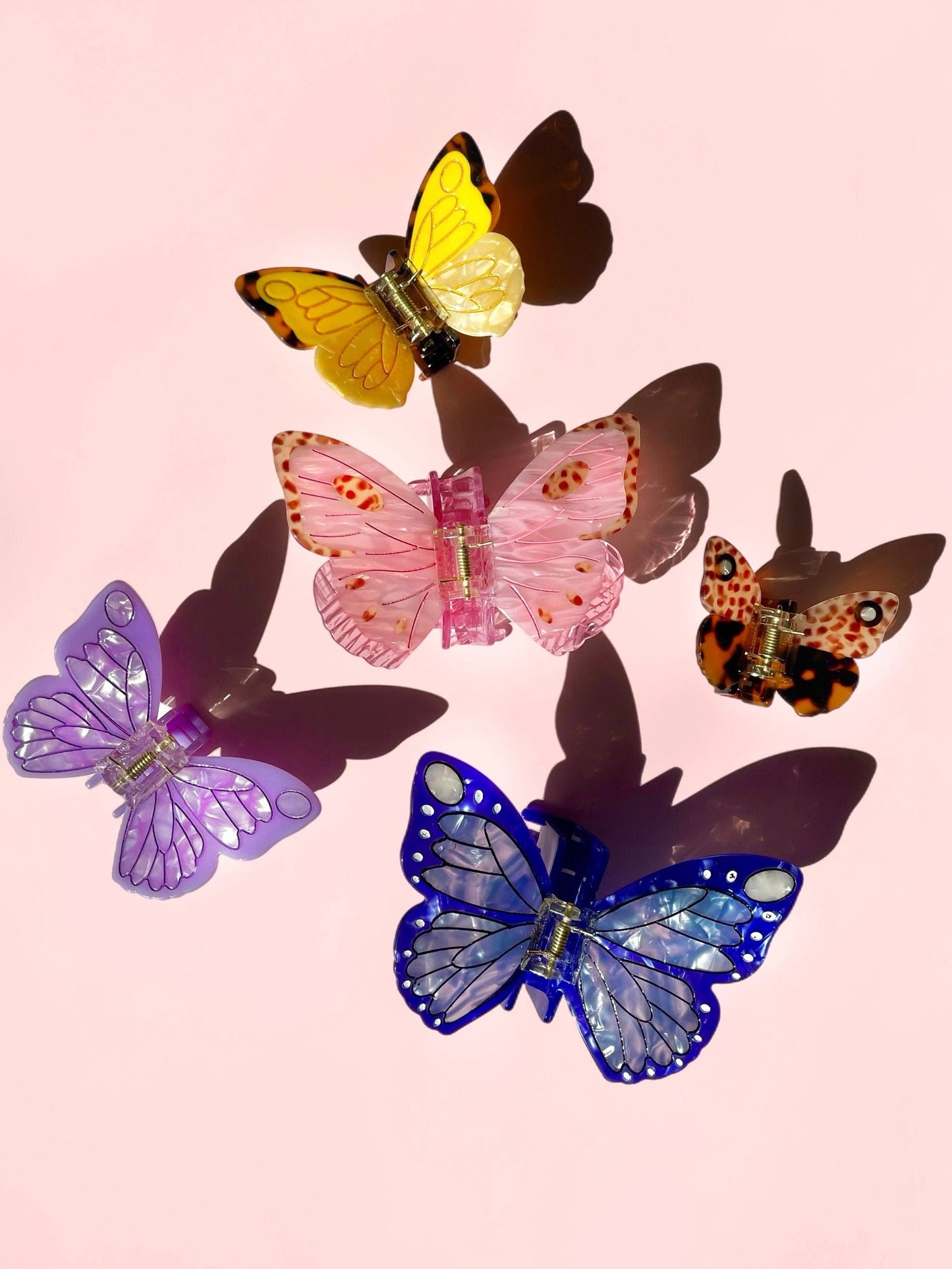 Colorful butterfly-shaped hair clips on a pink background