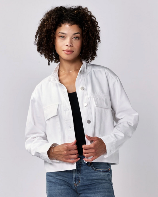 Front view of a model wearing the Dear John Cleo denim jacket in white with jeans standing in front of a white wall.