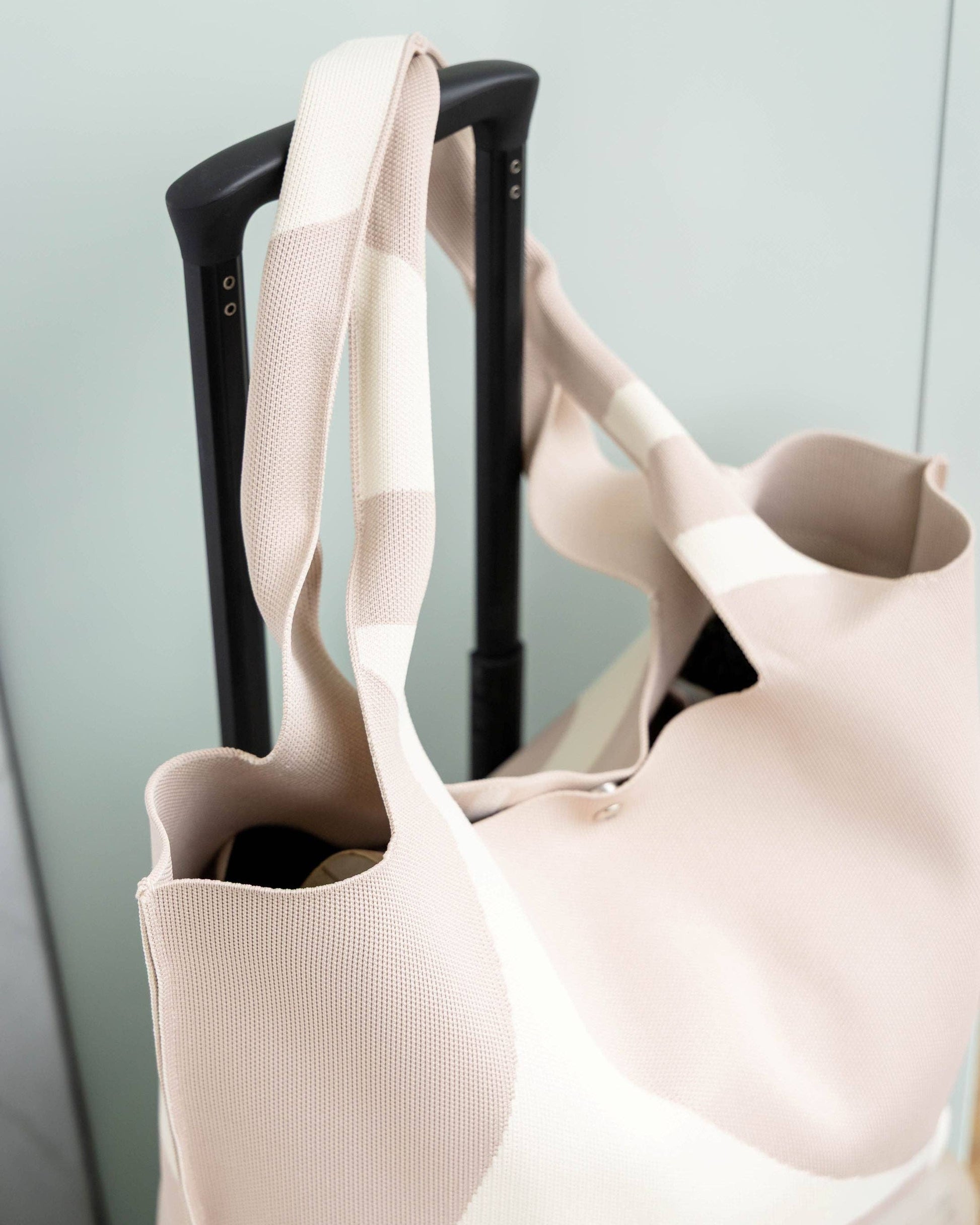 Beige tote bag with a black handle on a light gray background