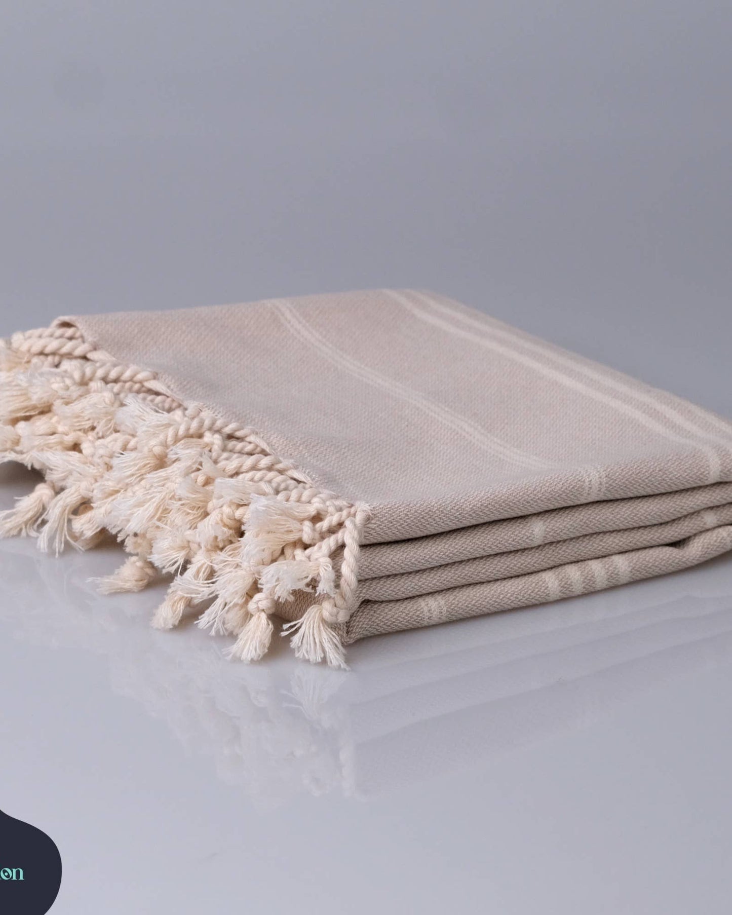 Beige towel with tassels on a light gray background, featuring the Kalladon brand.