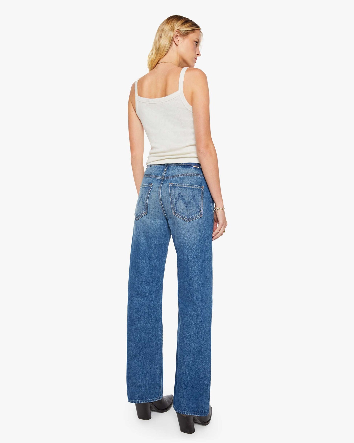 Woman wearing blue jeans and a white top on a white background