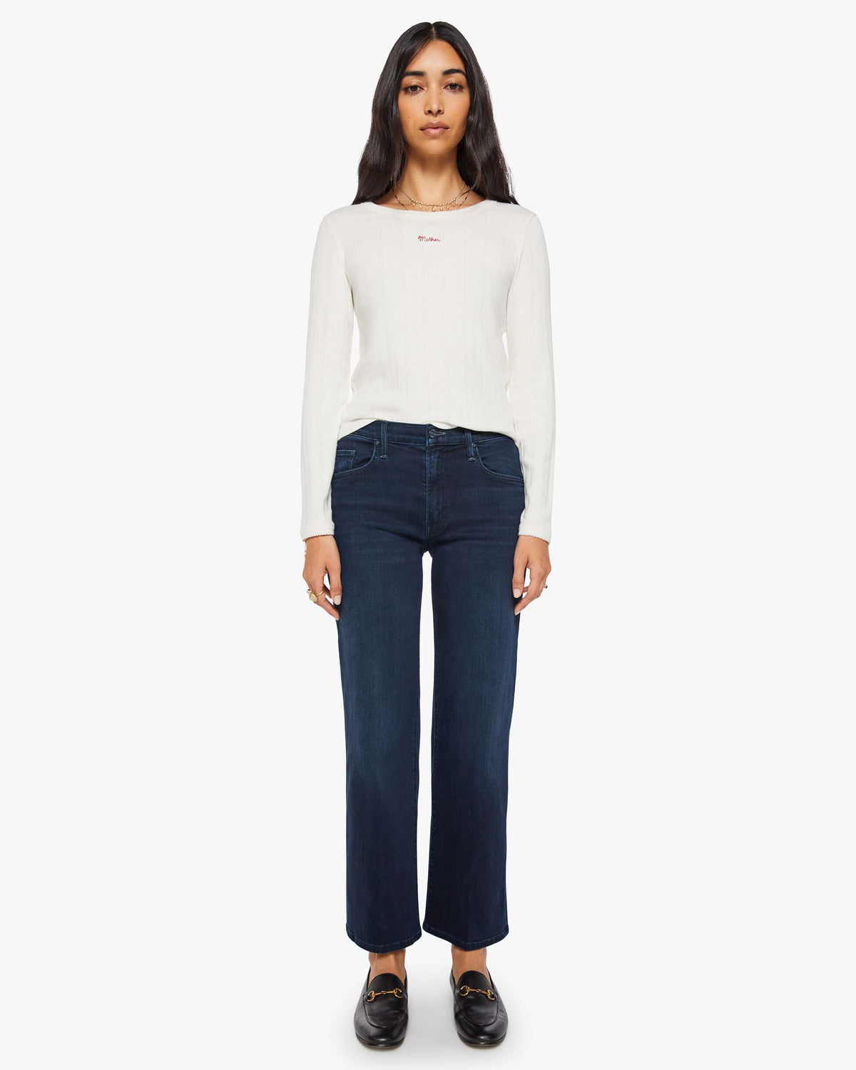Woman wearing a white long-sleeve shirt and dark blue jeans on a white background