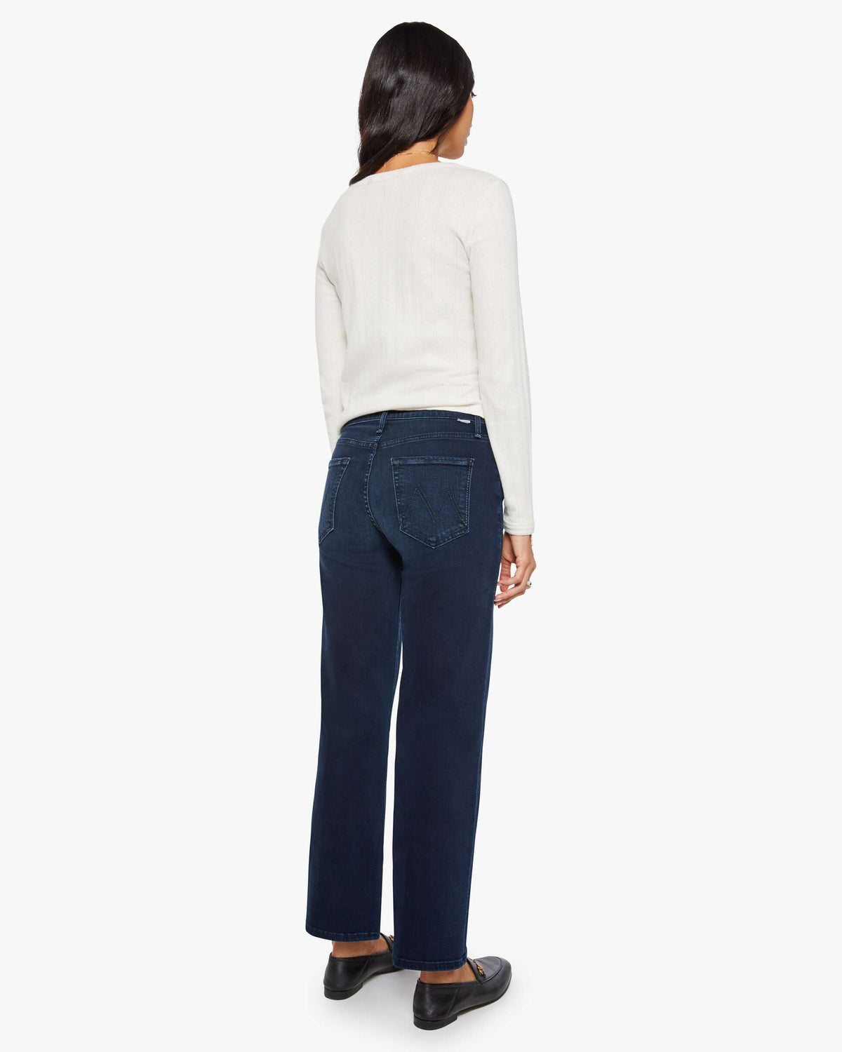 Person wearing a white sweater and dark blue jeans on a white background