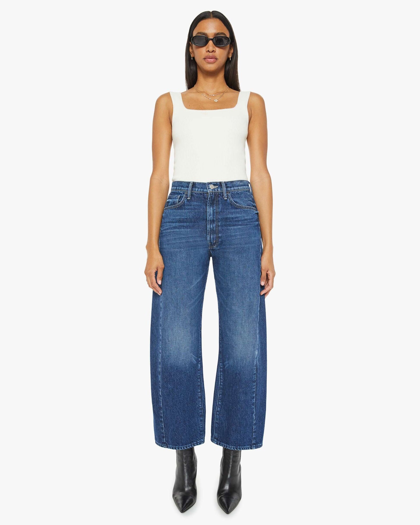 Woman wearing a white top and blue jeans on a white background