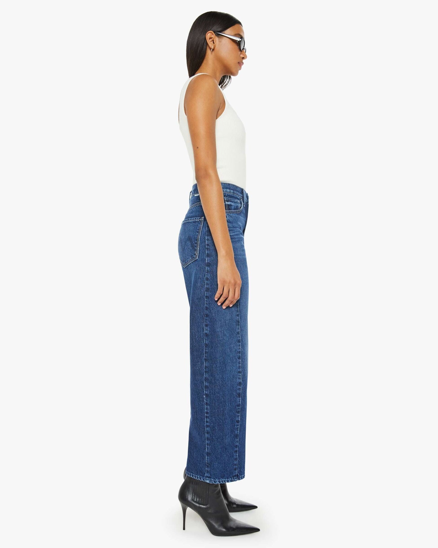 Woman wearing blue jeans and a white top on a white background