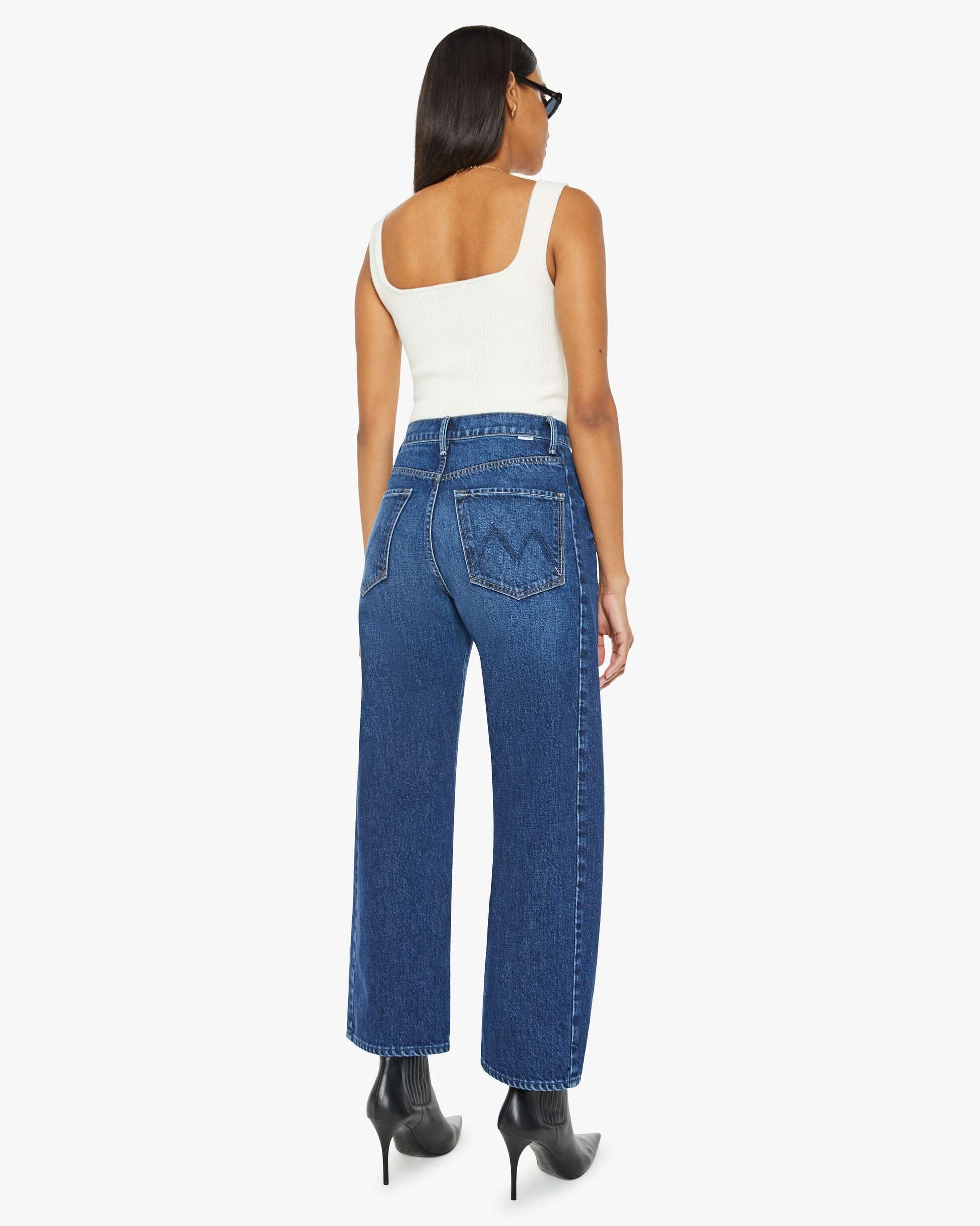 Woman wearing blue jeans and a white top on a white background