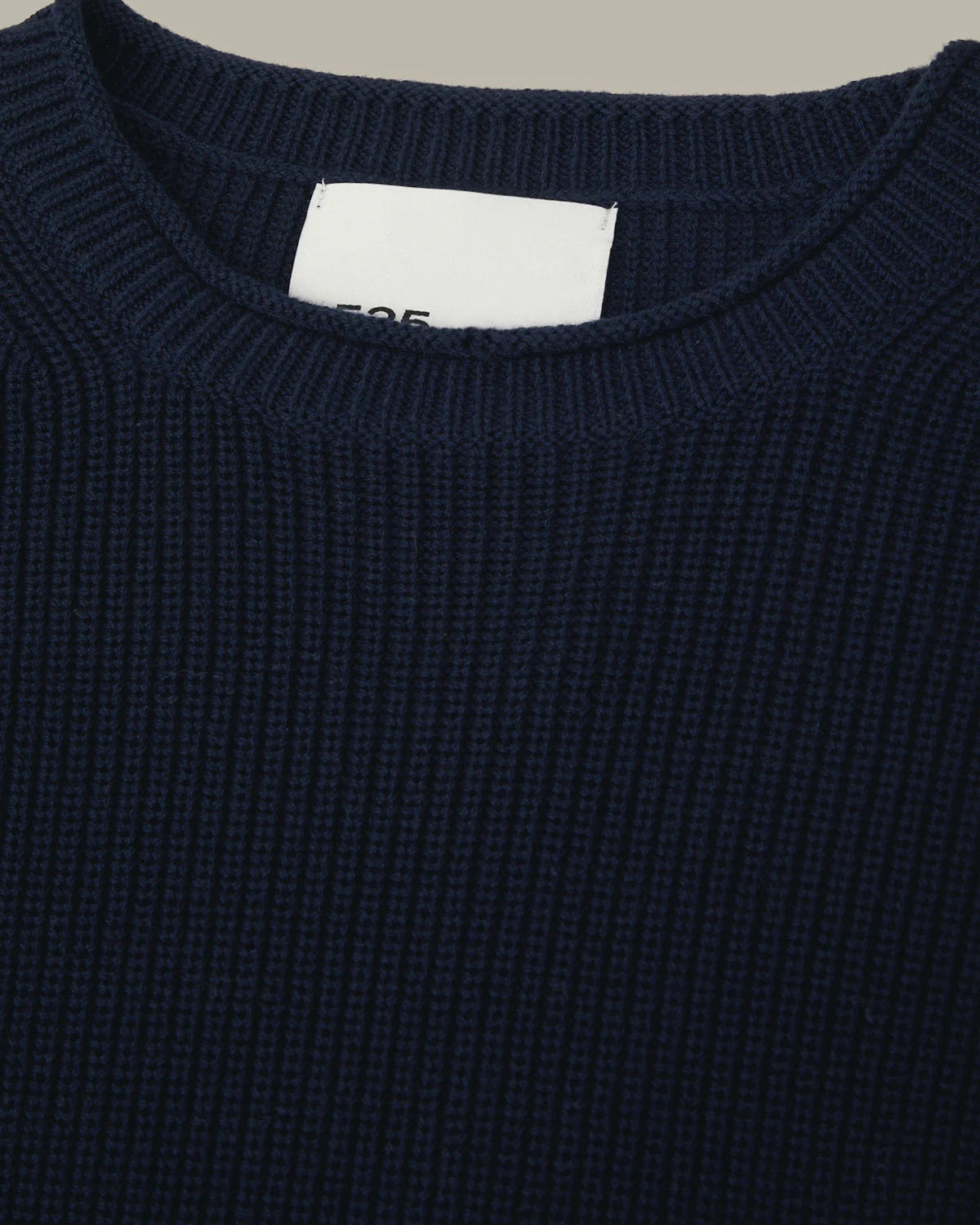 Navy blue sweater with a brand label on a beige background