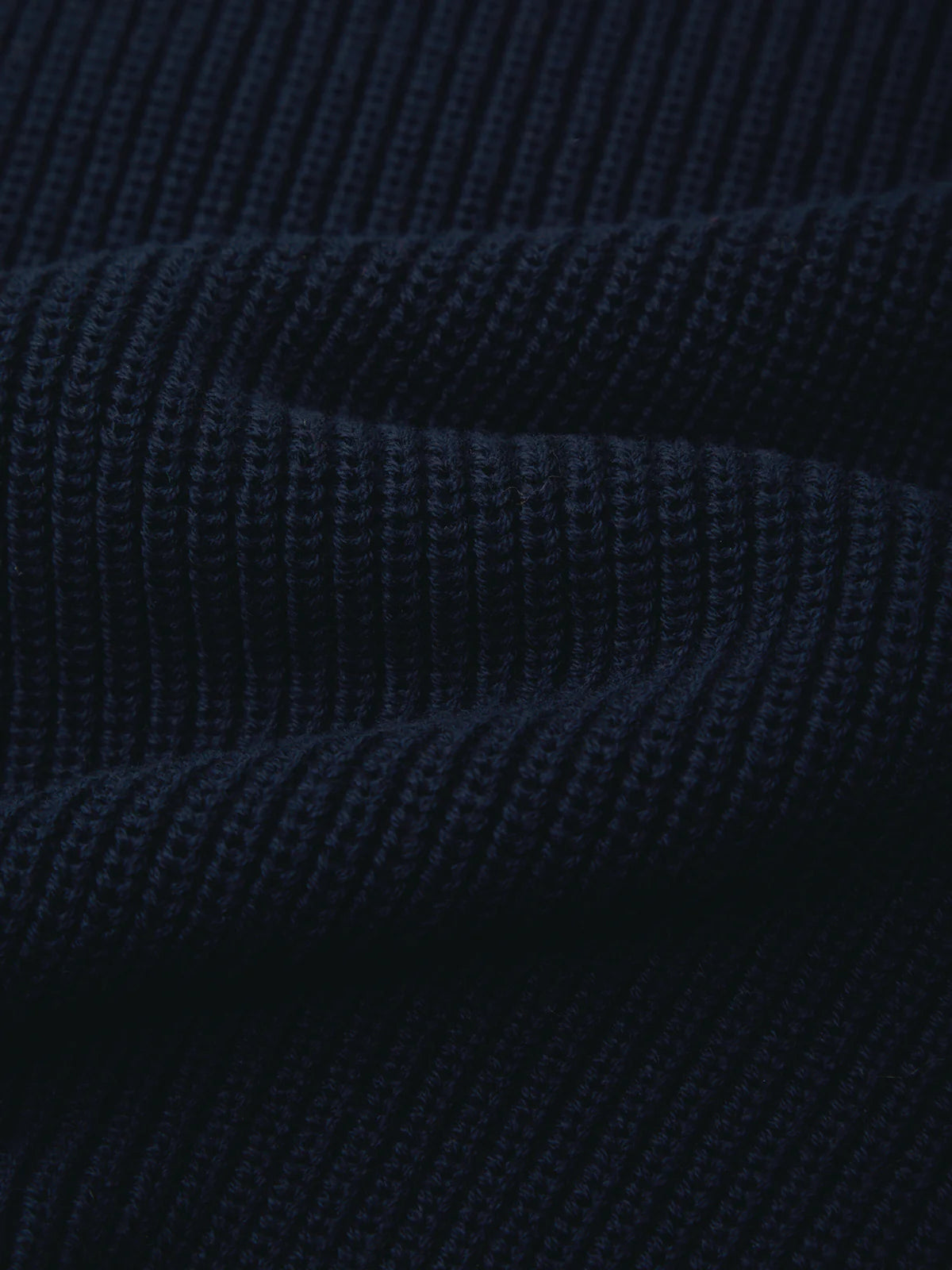 Close-up of a dark navy blue ribbed knit fabric texture with soft folds.