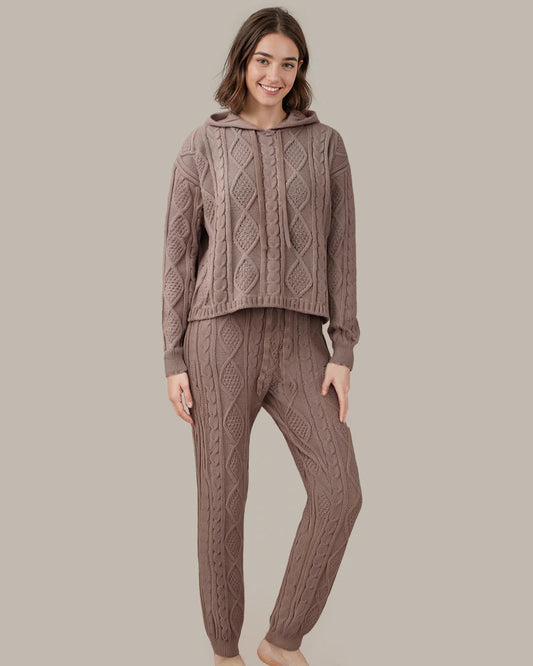 Woman wearing a brown cable knit hoodie and pants on a beige background