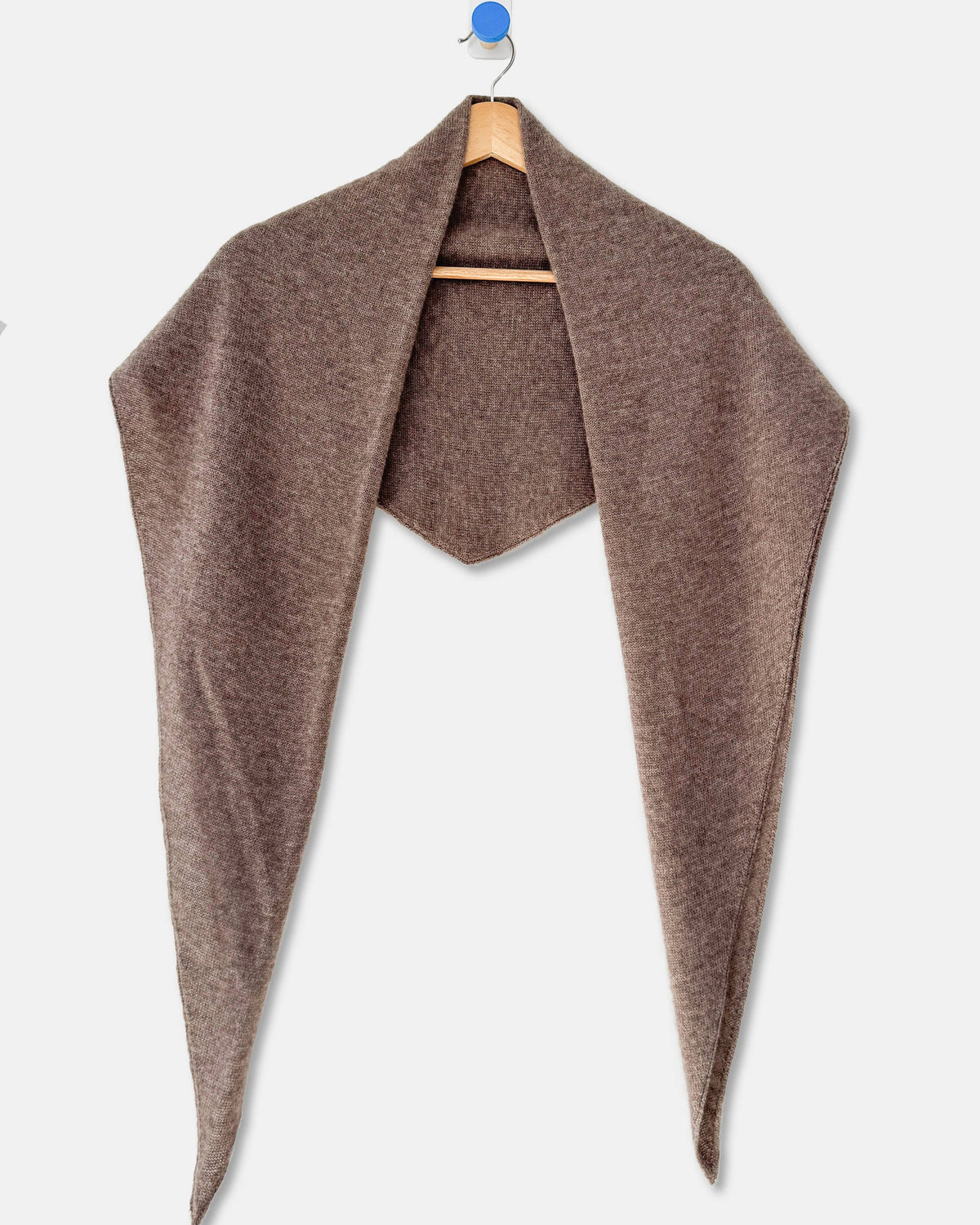 A brown open-front wrap or shawl draped over a wooden hanger against a light gray background.