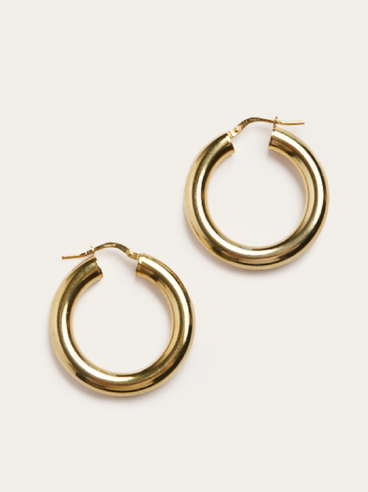 Gold hoop earrings on a light beige background