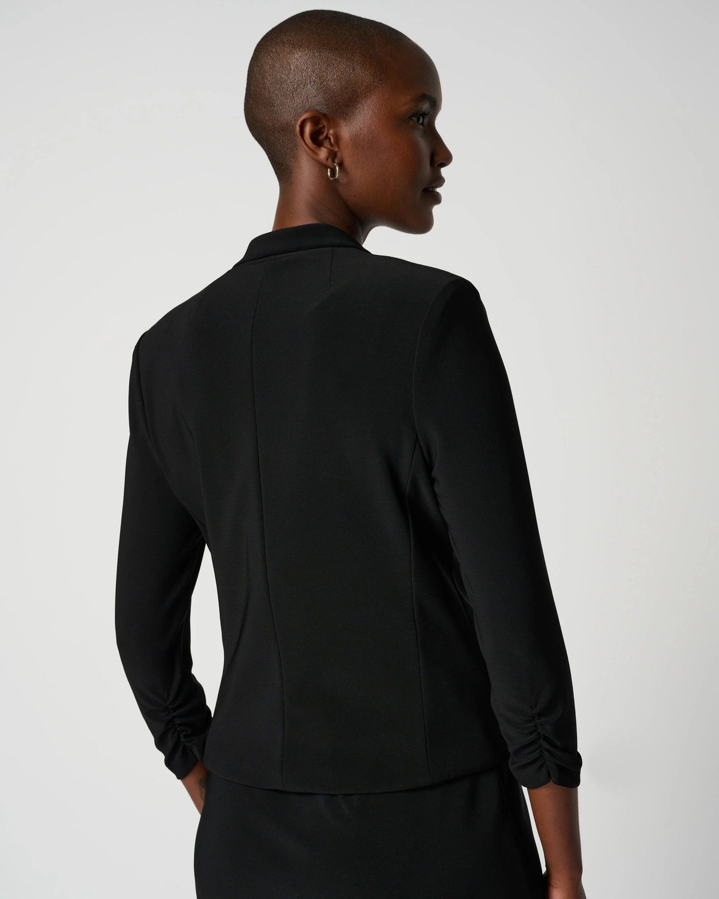 Person wearing a black suit on a plain background