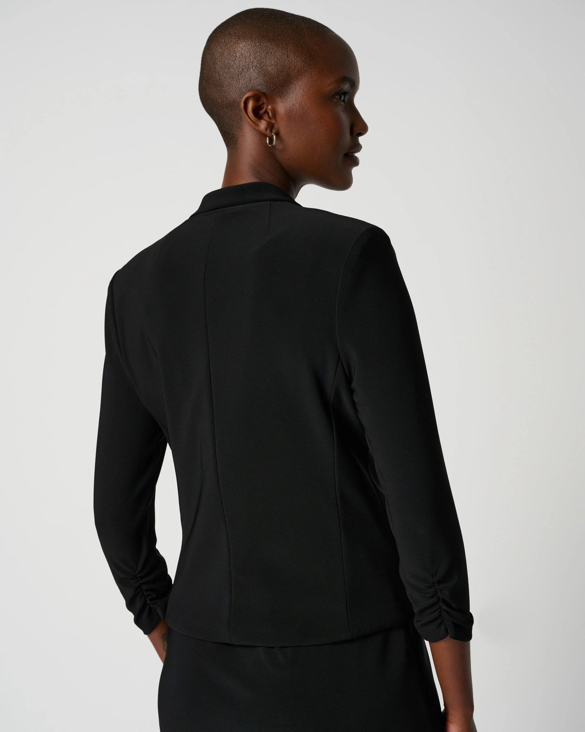 Person wearing a black suit on a plain background