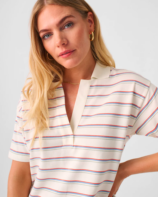 Model wearing Faherty Sunwash Piqued Polo in Tennis Stripe on a white background