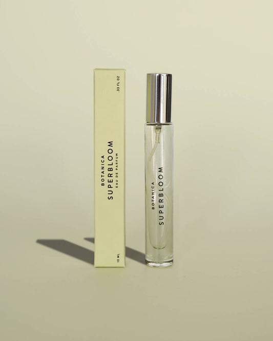Perfume bottle and packaging labeled 'Super Bloom' on a beige background