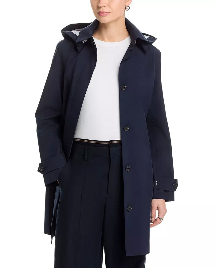 Person wearing a navy jacket over a white top with navy pants in front of a white background.