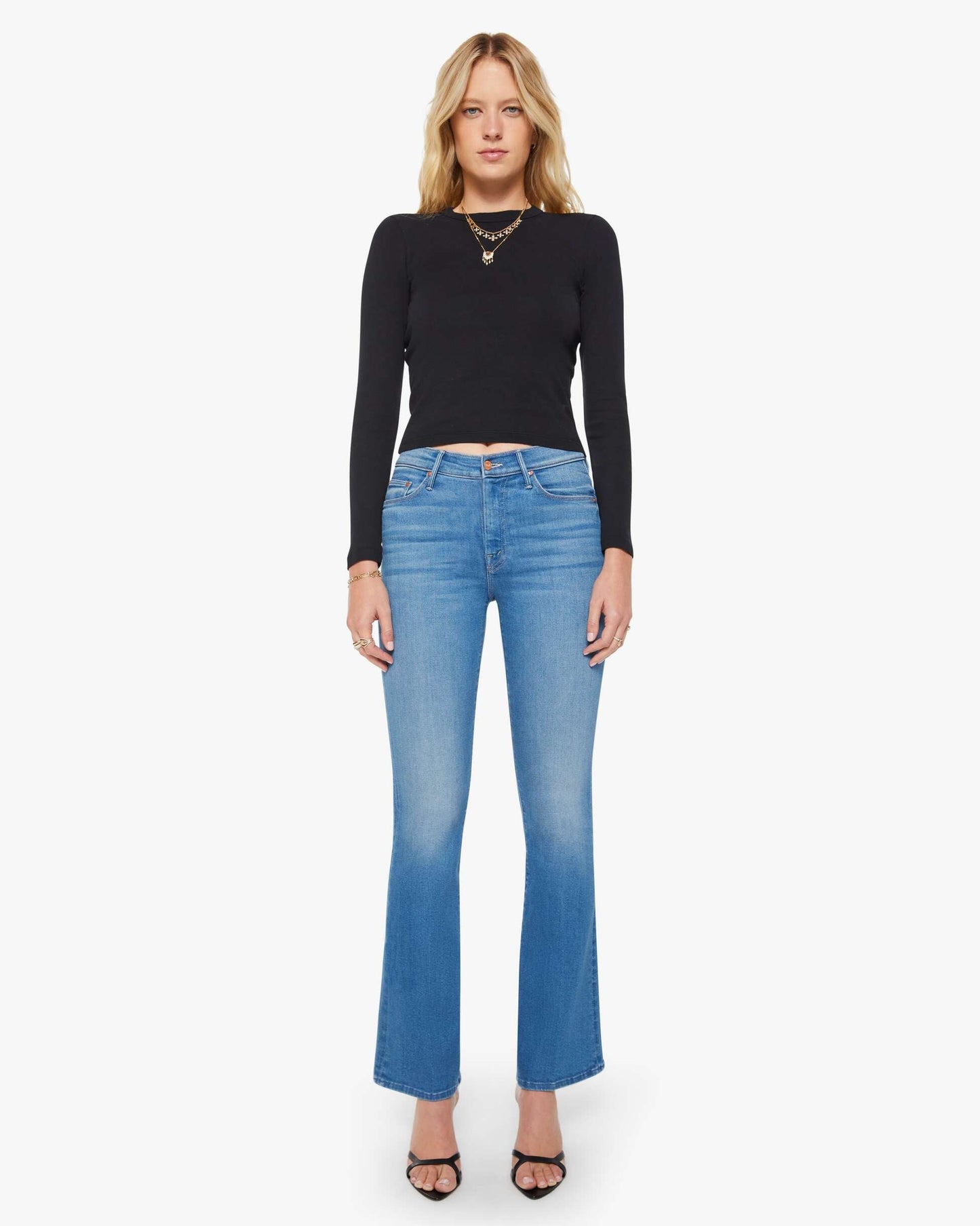 Woman wearing a black long-sleeve top and blue jeans on a white background