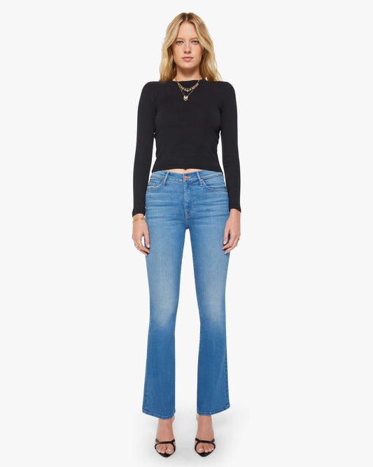 Woman wearing a black long-sleeve top and blue jeans on a white background