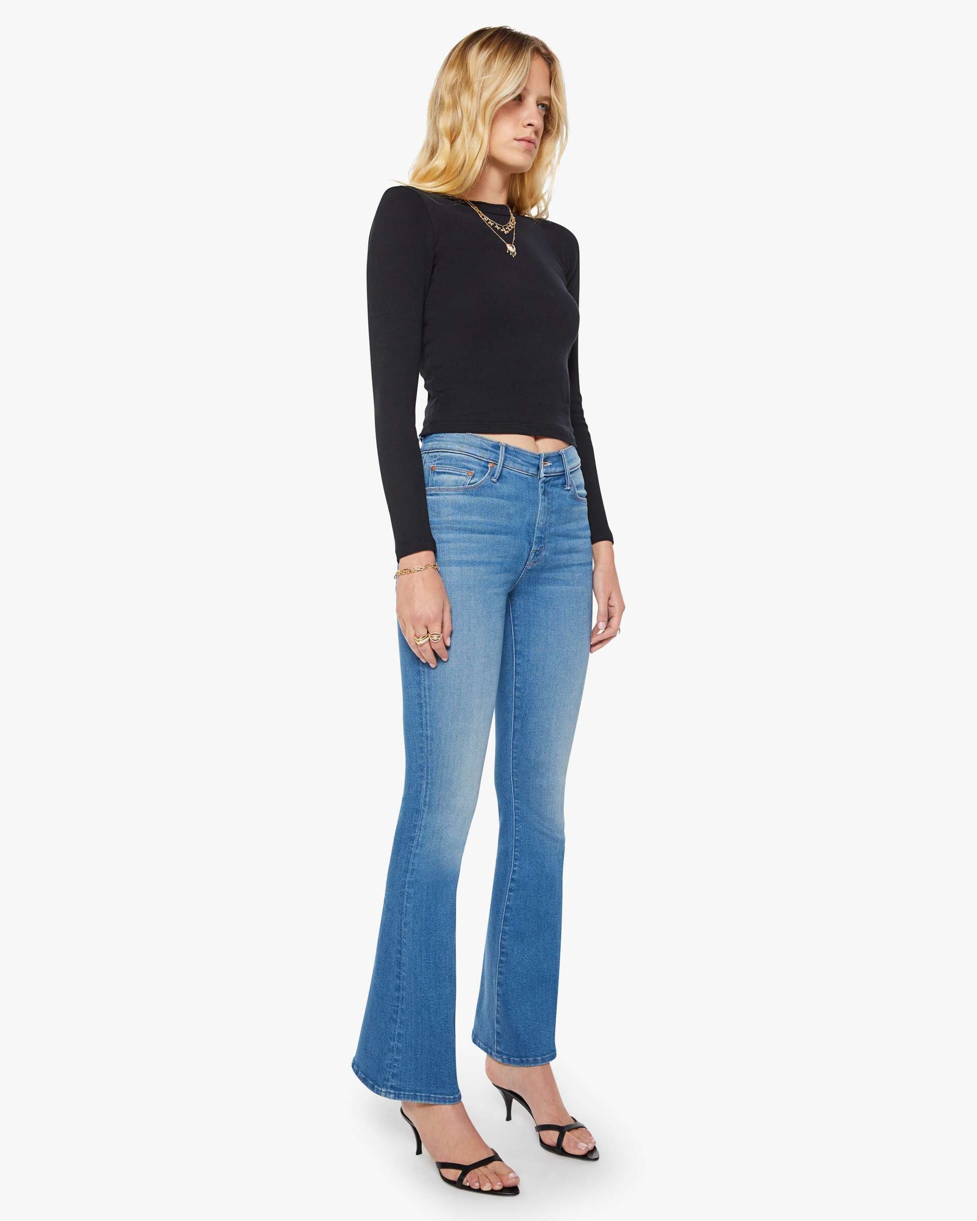 Woman wearing blue jeans and a black top on a white background