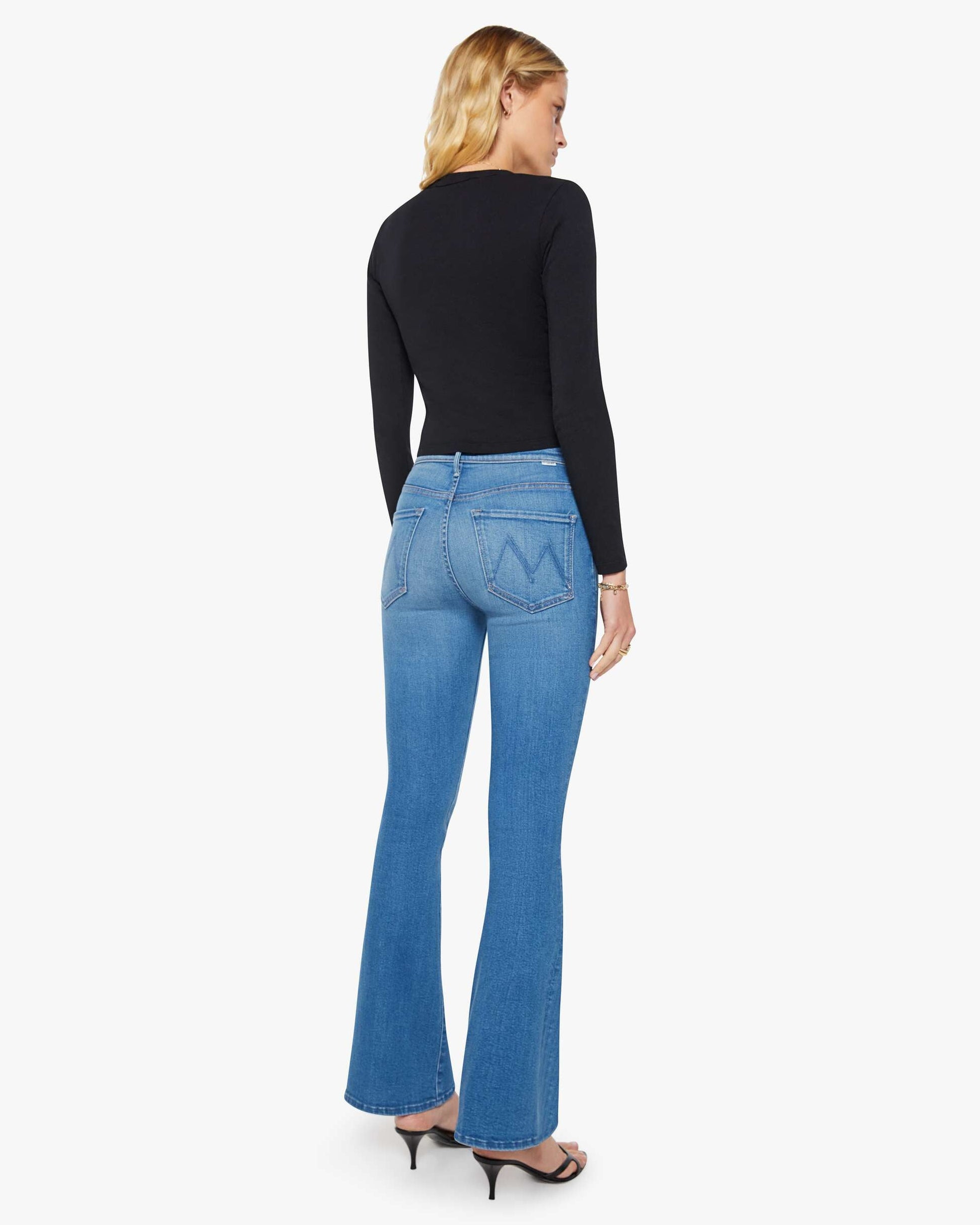 Woman wearing blue jeans and a black top on a white background