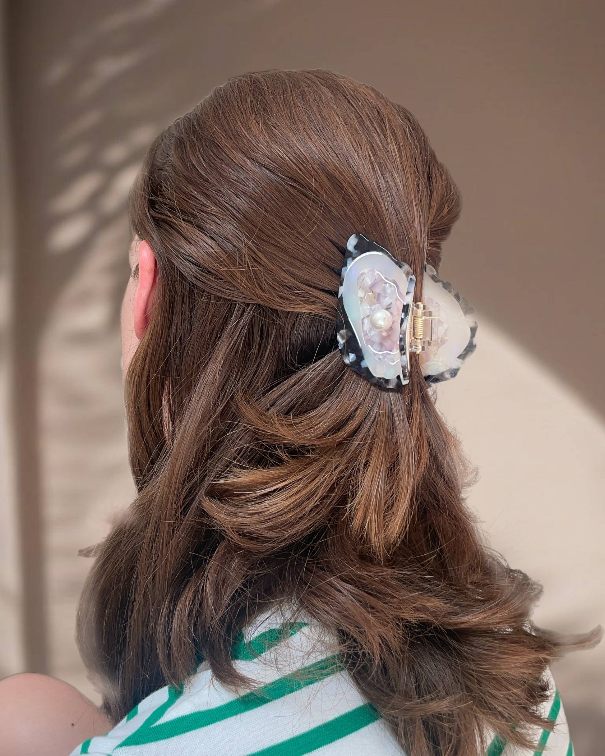 Person with styled hair featuring a decorative oyster hair clip against a neutral background