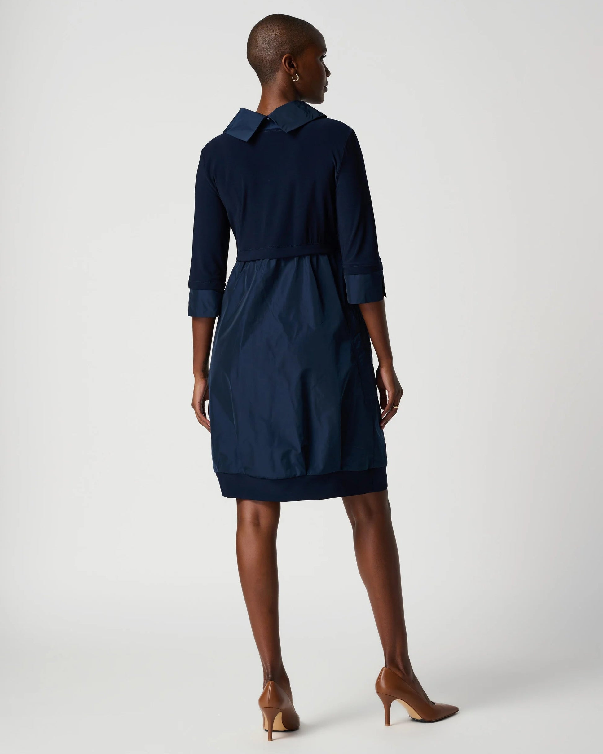 Woman wearing a navy dress with a white background