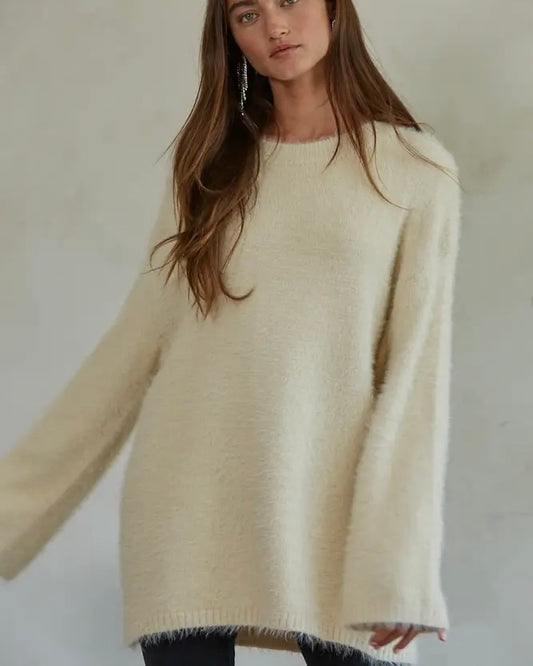 Model wearing By Together Fuzzy Pullover Sweater In cream wearing black leggings on a beige background 