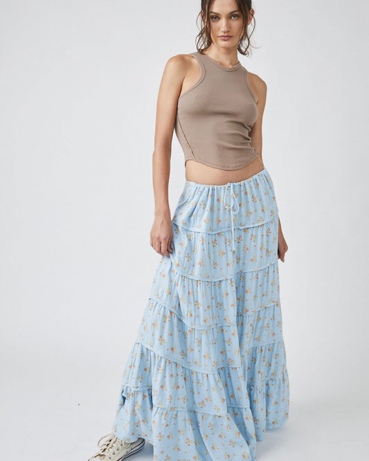 Model wearing Free People Nova Tiered Maxi Skirt in Robins egg blue floral color wearing a tan tank top on a white background