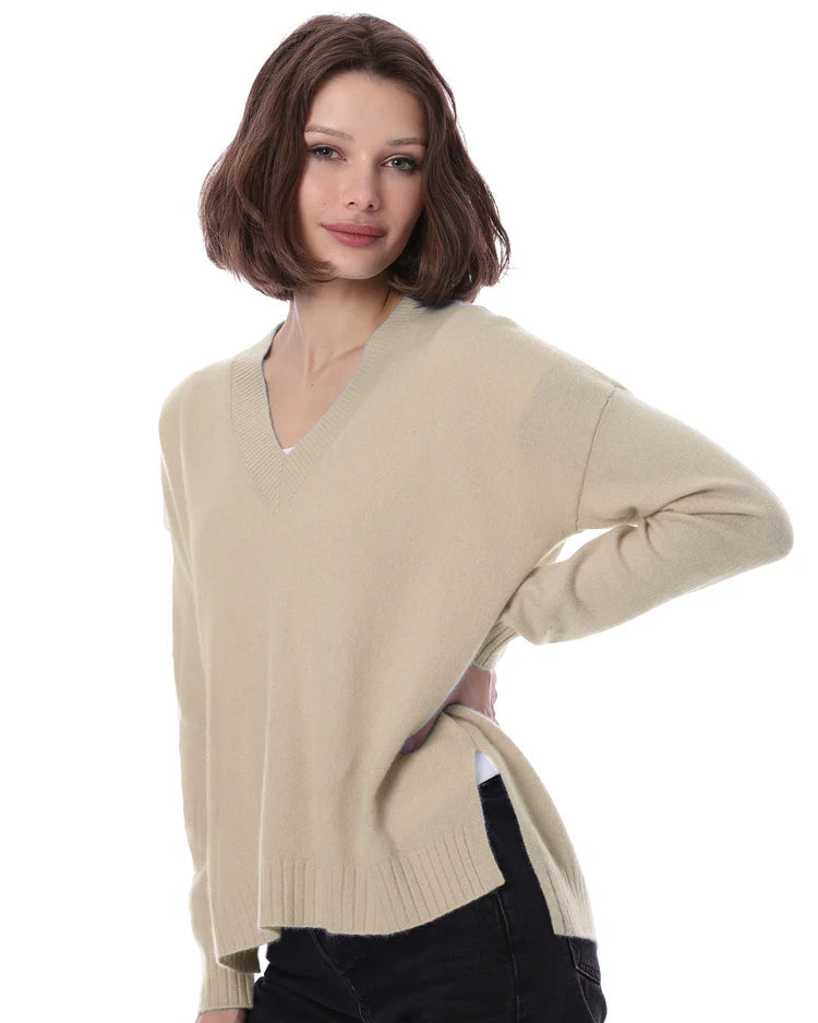 Woman wearing a beige sweater and black pants on a white background