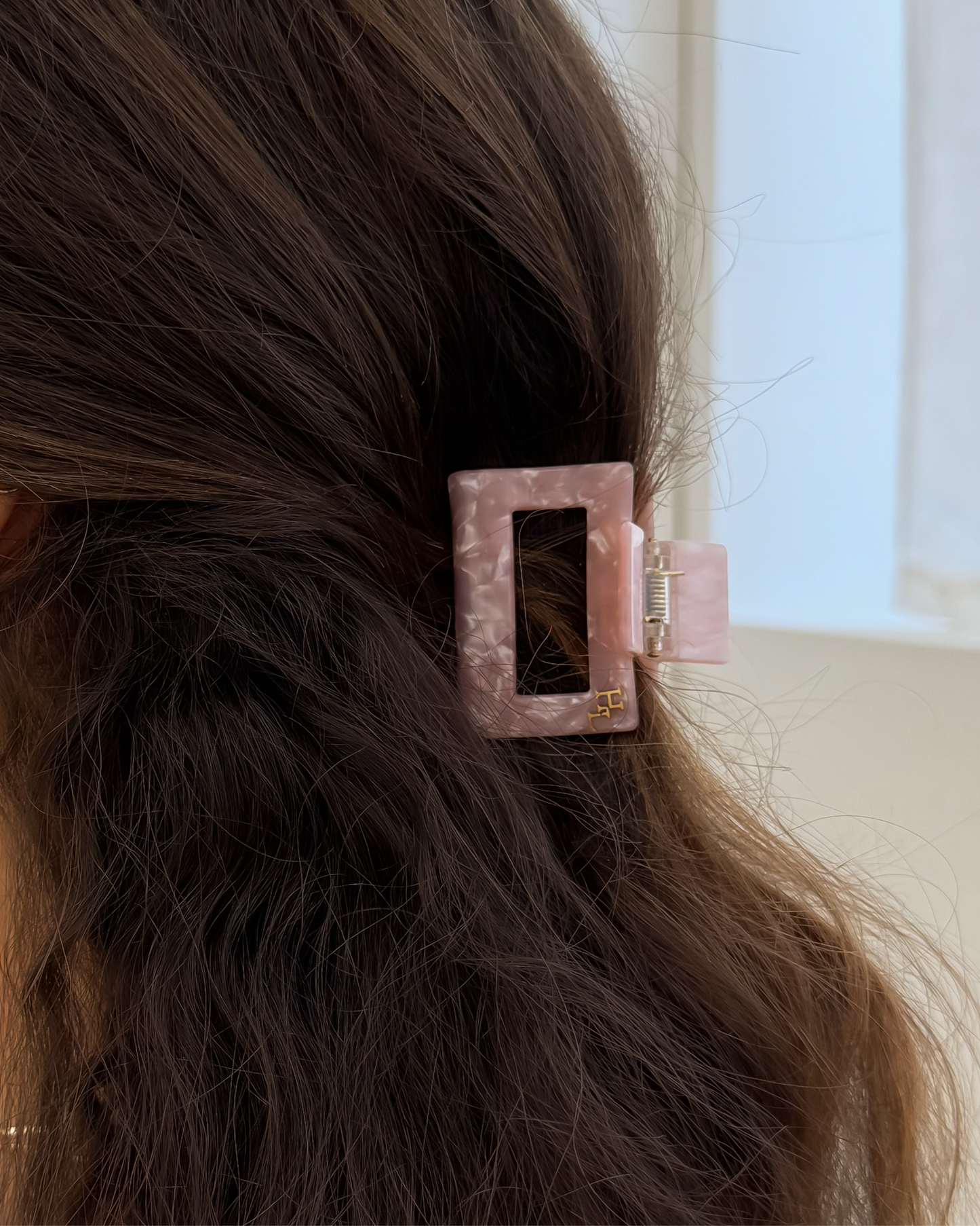 Person with a pink hair clip in their dark hair, wearing gold hoop earrings.