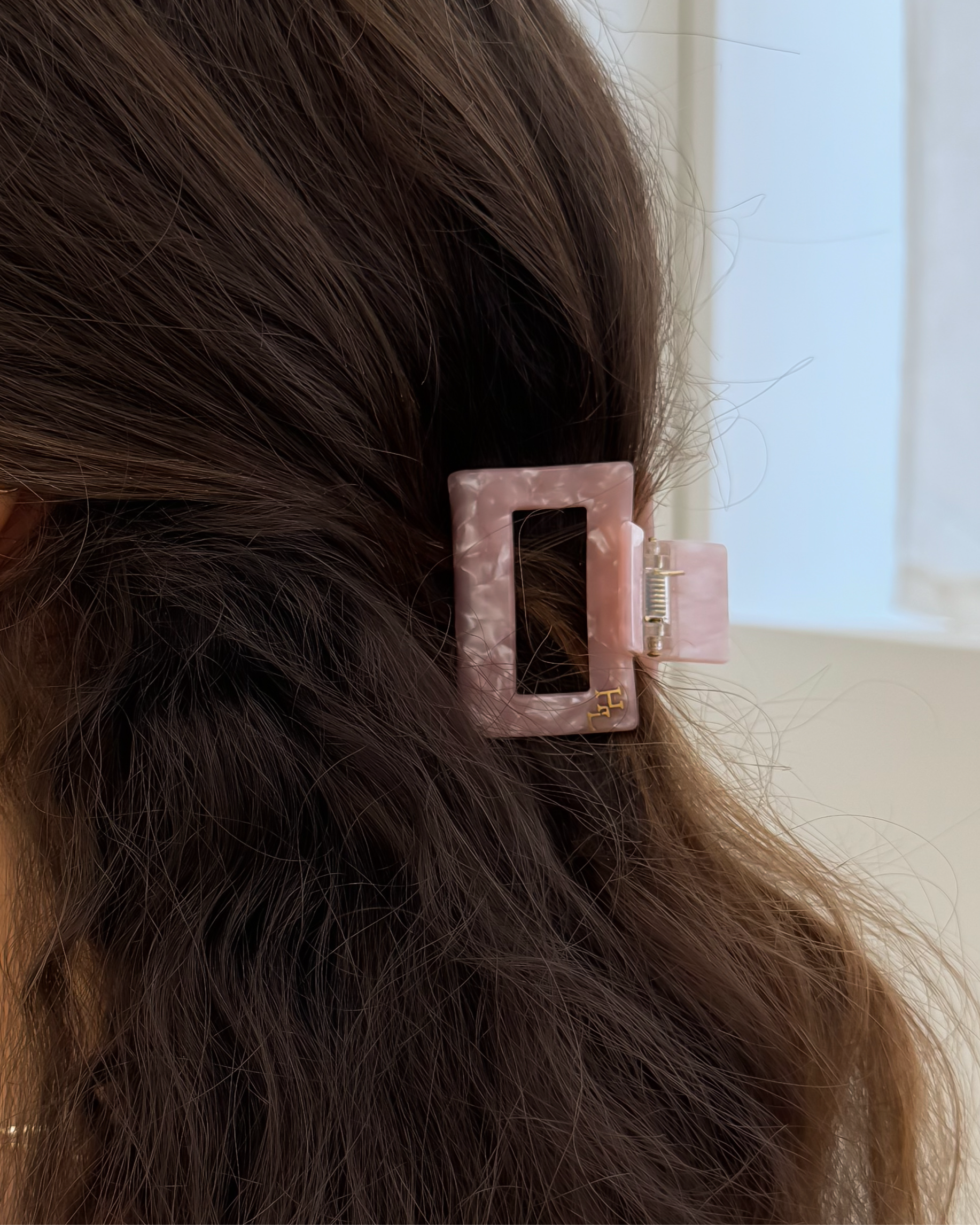 Person with a pink hair clip in their dark hair, wearing gold hoop earrings.