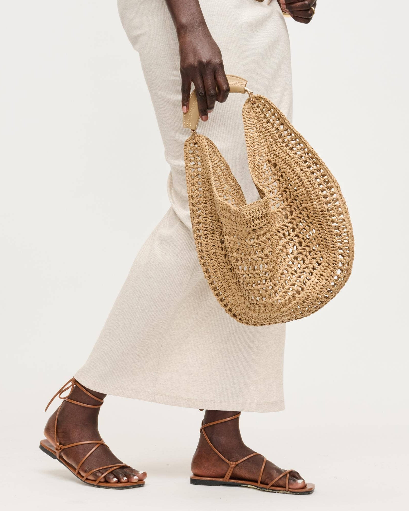 Person holding a woven straw bag with a plain background