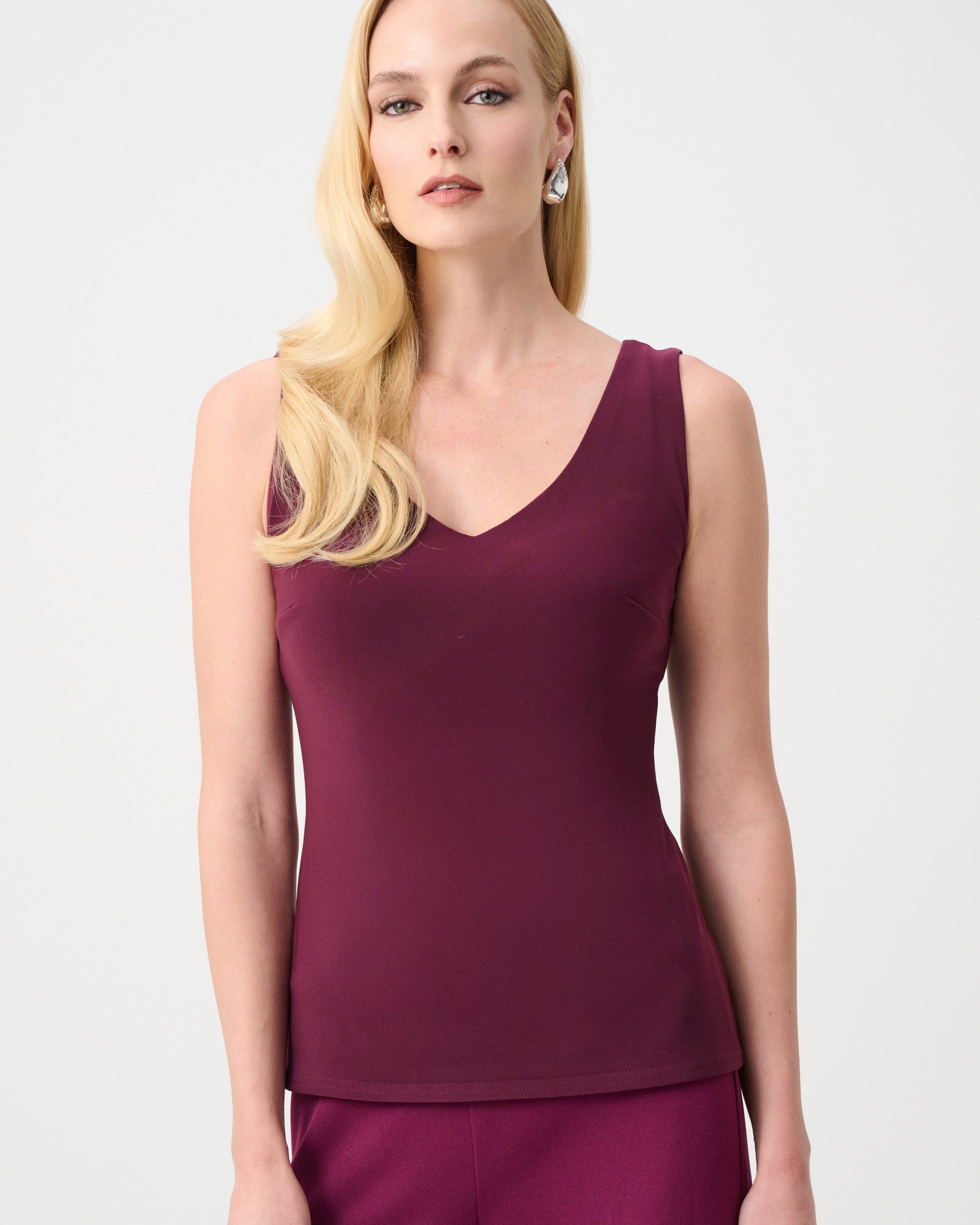 Woman wearing a purple sleeveless top and pants on a white background