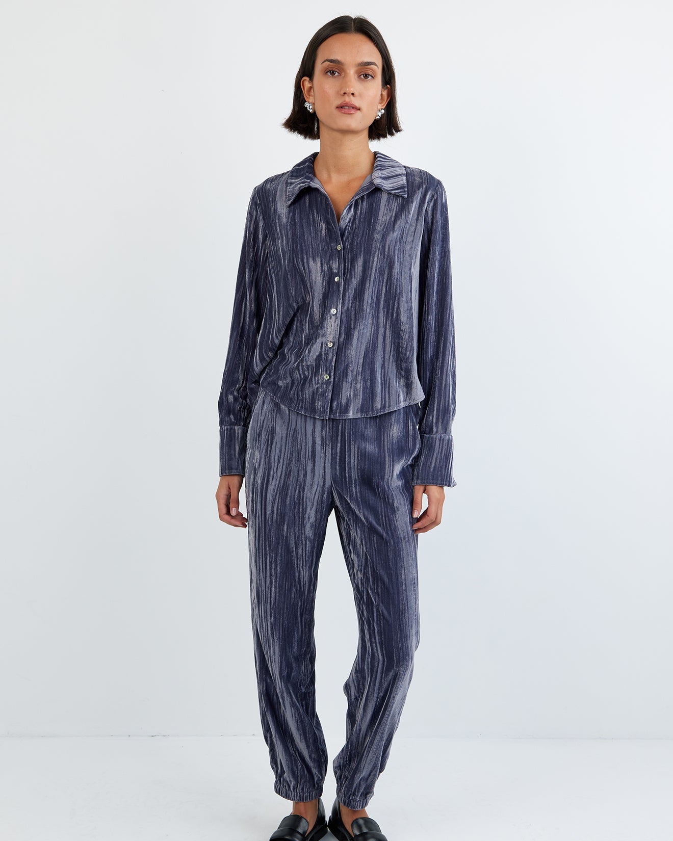 Person wearing a blue striped shirt and pants on a white background