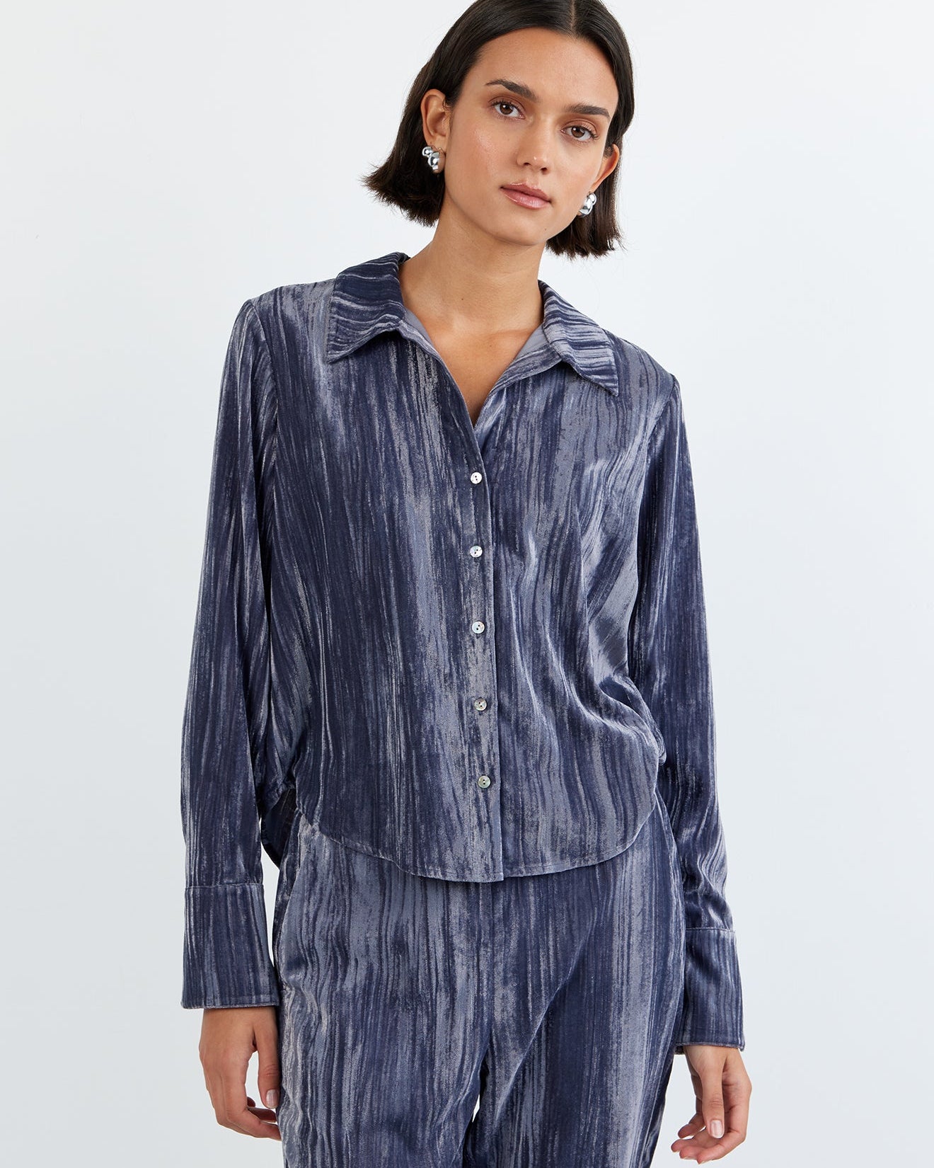 Woman wearing a blue striped shirt and pants on a white background