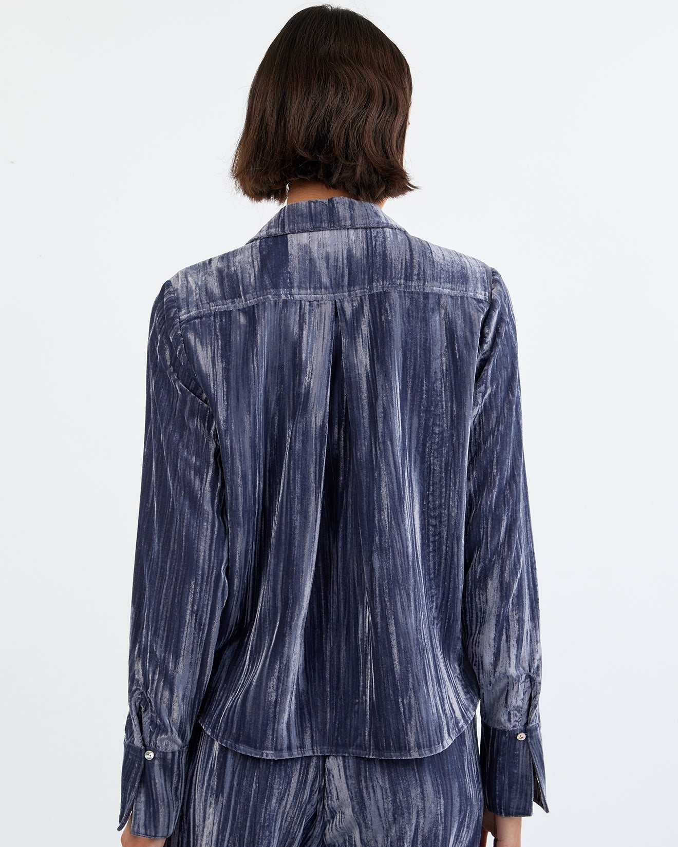 Person wearing a blue denim shirt and pants on a white background